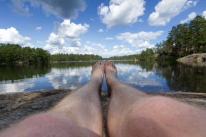 person is sitting at a characteristic scandinavian lake surrounded by pine trees person is sitting at a characteristic scandinavian lake surrounded by pine trees